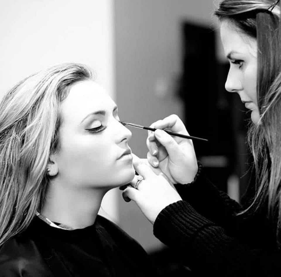 Makeup artist is expertly applying eyeliner to a woman's eyes.
