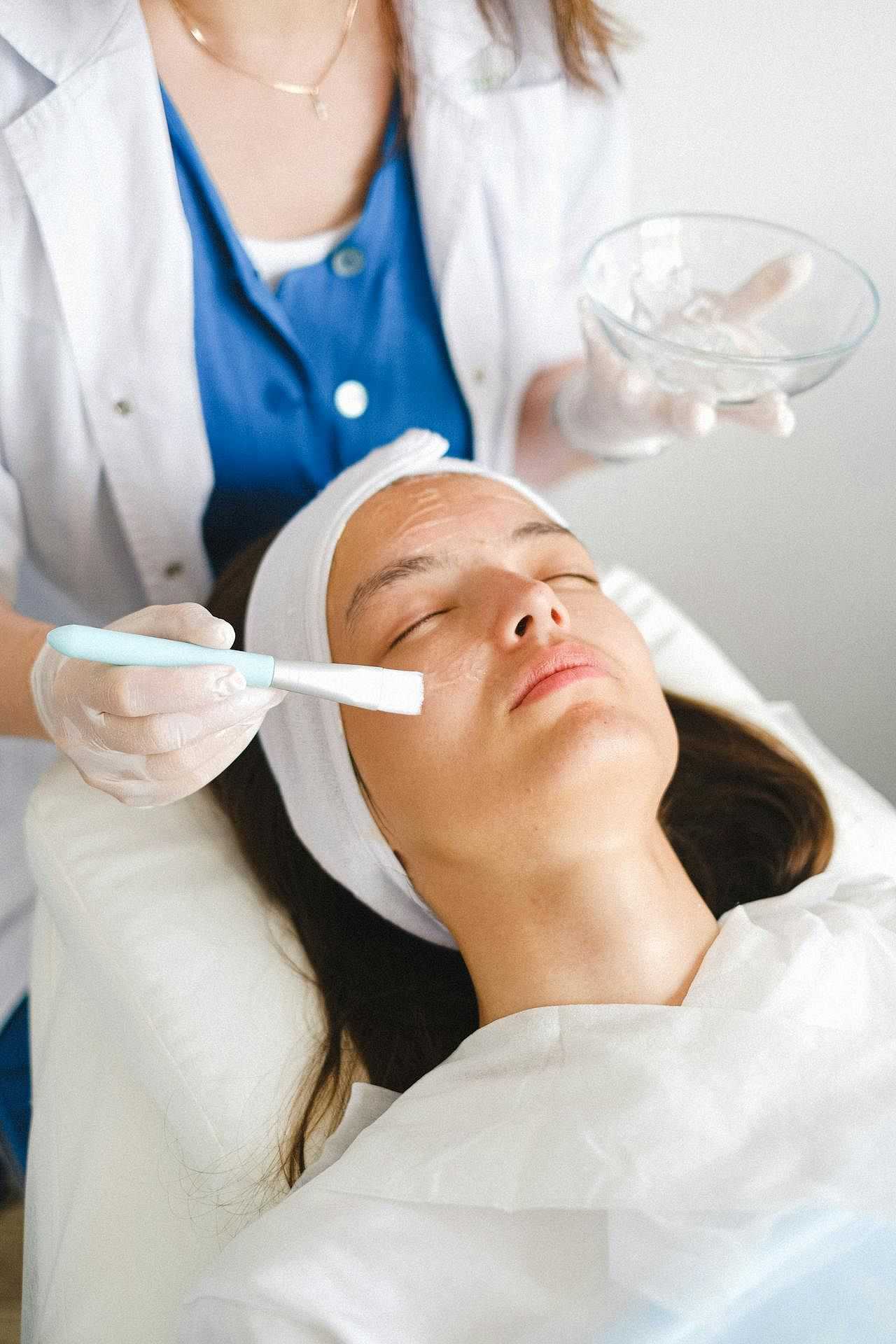 Woman receiving a facial treatment with a brush at a spa.