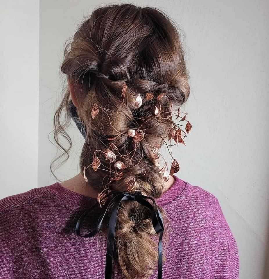 Intricate braided hairstyle with ornamental leaves and ribbon, viewed from the back.