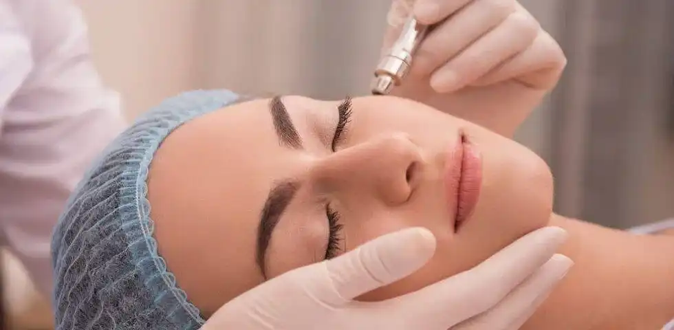 Woman receiving a facial treatment with a microdermabrasion device by a gloved professional.